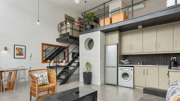 Eine moderne Loftswohnung mit Essbereich, Wohnzimmer, Küche und einer Treppe zu einer oberen Ebene.