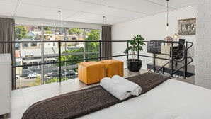 Ein modernes Hotelzimmer mit großem Fenster, einem Bett, einem Schreibtisch und Blick auf die Stadt.