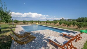 Una piscina con lettini e un solarium piastrellato.