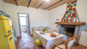 Zona pranzo con tavolo apparecchiato per quattro, frigorifero giallo e camino con mosaico colorato.