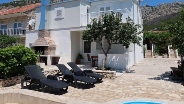 A white building with a stone chimney, a pool, and lounge chairs. - Vacation home Kevin by Interhome (Orebić/Viganj)