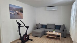A living room with a grey sofa, a small wooden coffee table, and an exercise bike. - Vacation home Kevin by Interhome (Orebić/Viganj)