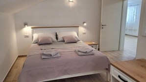 A bedroom with a bed, bedside tables, a nightstand, an air conditioning unit, and a view of the outside through a door. - Vacation home Kevin by Interhome (Orebić/Viganj)