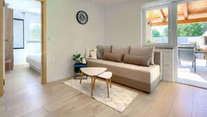 A modern living room with a sofa, a small table, and a clock on the wall. - Vacation home Laura by Interhome (Štinjan)