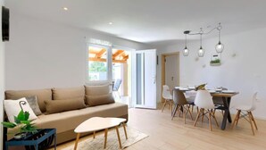 A modern living room with a sofa, coffee table, and dining area with chairs and a table. - Vacation home Laura by Interhome (Štinjan)