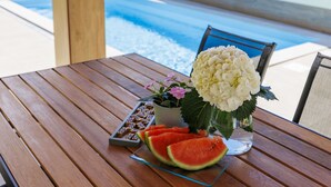 A wooden table with a glass tray holding watermelon slices and a vase with flowers. - Vacation home Laura by Interhome (Štinjan)