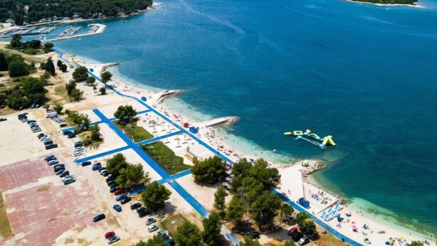 An aerial view of a coastal area with a beach, parking lots, and a marina. - Vacation home Laura by Interhome (Štinjan)