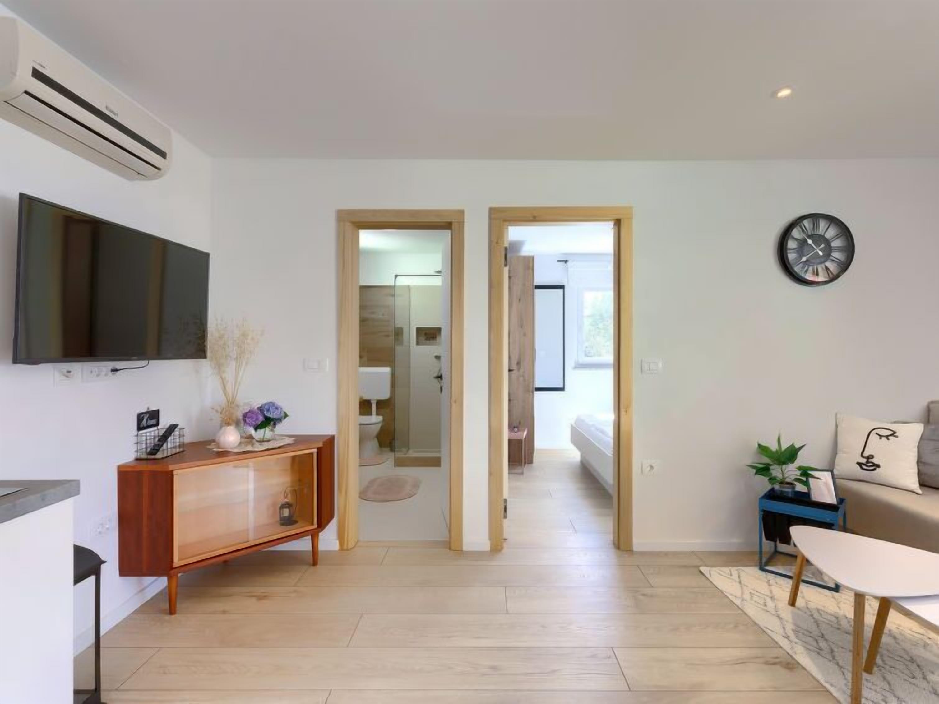 Una sala de estar moderna con televisor, mueble de madera y sofá.