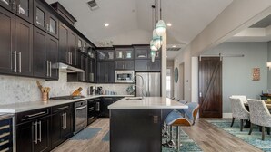 A modern kitchen with dark cabinetry, stainless steel appliances, and a central island.