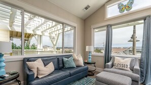 A modern living room with a blue sofa, a grey armchair, and a view of the city through large windows.