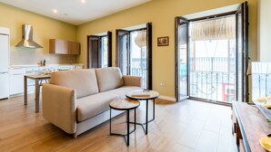 A modern living room with a sofa, a small round table, and a kitchen area in the background.