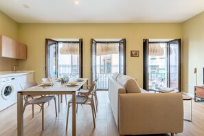 A modern living room with a sofa, dining table, chairs, and a washing machine. - Castilla, 1-bedroom in Triana (Sevilla)