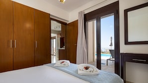 A hotel room with a large bed, wooden wardrobe, and a view of a swimming pool. - Villa Lia with private ecologic pool and amazing view! (Kontopoula)
