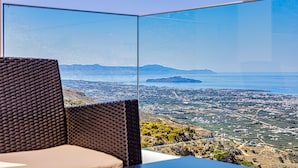 A panoramic view from a high vantage point, likely from a balcony or terrace, overlooking a coastal city with a clear sky. - Villa Lia with private ecologic pool and amazing view! (Kontopoula)