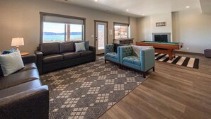 A spacious living room with a pool table, two sofas, and a view of the ocean.