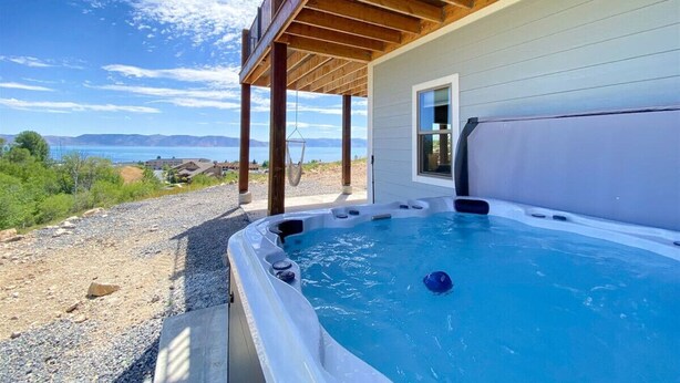 A hot tub with a view of the ocean, a wooden deck, and a covered area with a door.