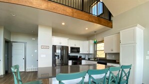 A spacious kitchen with white cabinets, a stainless steel refrigerator, and a central island with bar stools.