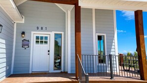 A house with a white exterior, a porch with wooden beams, and a number '981' on the door.