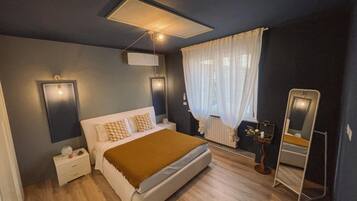 Een moderne slaapkamer met een bed, nachtkastjes, een spiegel en een plafondlamp.