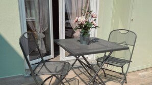 A metal table and chairs set on a patio with a sliding glass door and a potted plant. - WellHome   "Ruchè" Apartment (ASTI)
