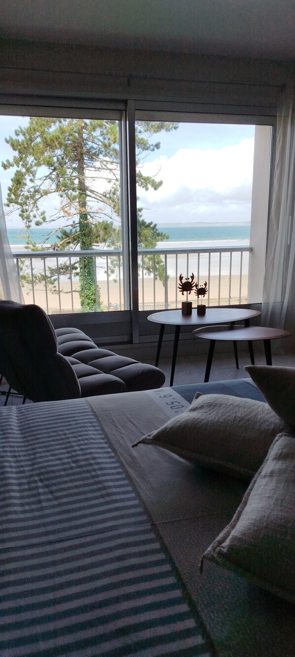 A balcony with a view of the beach and ocean, a sofa, a small table, and a potted plant. - An impressive estate overlooking the beautiful Bay of Douarnenez! (Douarnenez)