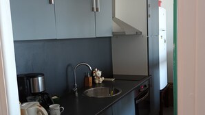 A compact kitchen with a washing machine, a coffee maker, and a sink.