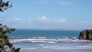 A beach with waves, a rocky outcrop, and picnic tables.