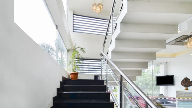 Un escalier moderne avec des rampes en métal, une plante en pot et un téléviseur à écran plat fixé au mur.