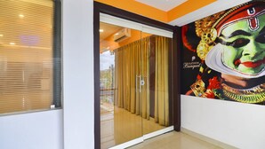 L’entrée d’un hôtel, avec une porte en verre, un rideau et une fresque représentant un visage sur le mur.