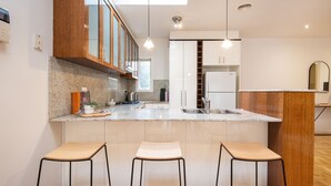 A modern kitchen with a central island, bar stools, and a built-in refrigerator. - Pet Friendly - Elwood Sanctuary - walking distance to the beach (Elwood)