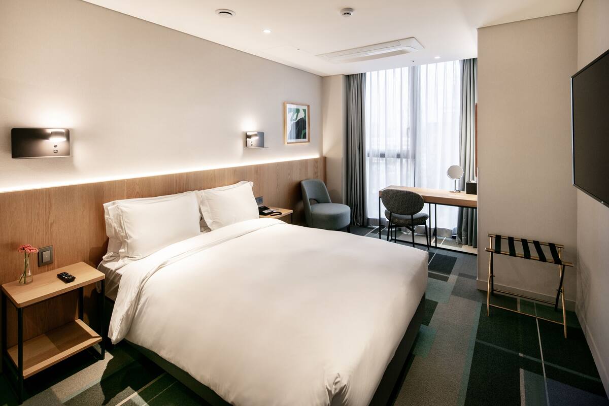 Una habitación de hotel con una cama grande, un escritorio, una silla y un televisor.