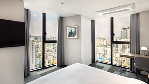 A hotel room with a large bed, a desk, and a chair. It has a city view through large windows. - G3 Hotel Chungmuro (Seoul)