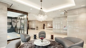 A modern lobby with a round marble table, grey sofas, and a unique chandelier. - G3 Hotel Chungmuro (Seoul)
