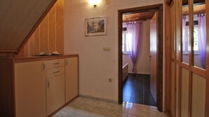 A narrow hallway with wooden cabinets and a tiled floor, leading to a room with a window and curtains. - Apartment 2192/56814 (Istria - Pula), 3000m from the beach (Pula)