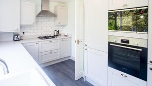 Une cuisine moderne avec des meubles blancs, un four Bosch et une cuisinière à gaz.