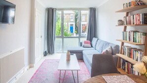 Un salon moderne avec un canapé, une table basse, une bibliothèque et un téléviseur fixé au mur.