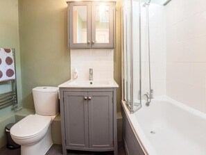 A bathroom with a toilet, a sink with a mirror above it, and a shower area.