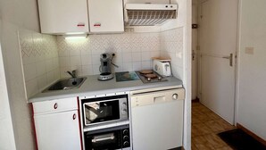 A compact kitchen with white cabinets, a built-in oven, a coffee maker, and a toaster.