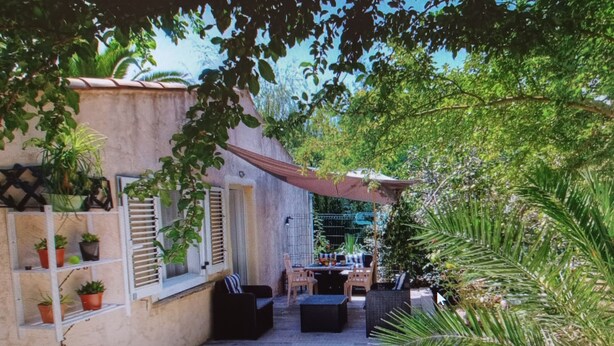 A covered patio area with outdoor seating, surrounded by potted plants and a white fence. - à 650 Metres d Altitude au Cœur de l Alta Rocca Entre Porto Vecchio et Propriano (Levie)