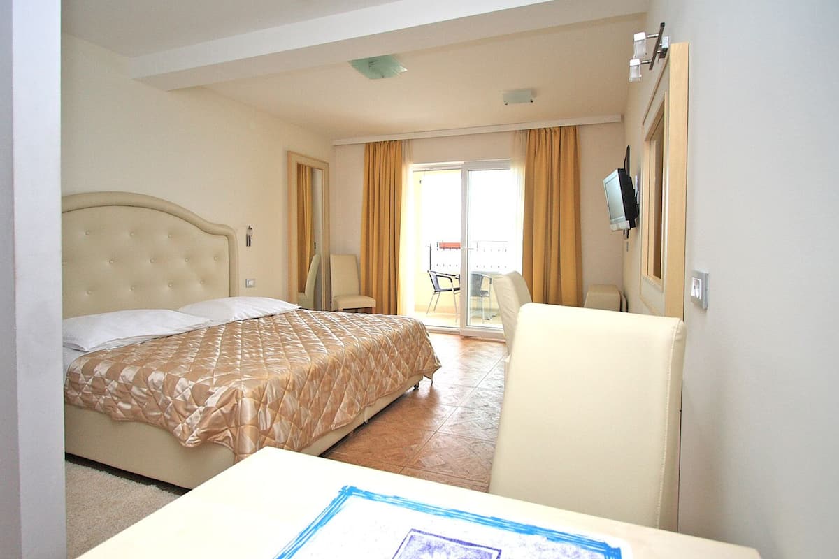 A hotel room with a bed, a chair, a desk, and a TV.