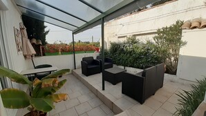 Un patio couvert avec des meubles d’extérieur, une table et des plantes en pot.