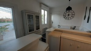 Une cuisine avec des armoires blanches, un plan de travail en bois et une horloge murale.