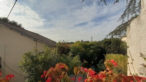 Une cour avec un bâtiment blanc, de la verdure et un ciel dégagé.
