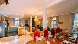 A spacious dining area with a wooden table set for six, surrounded by red upholstered chairs. - Le Moulin du Pont (Mezin)