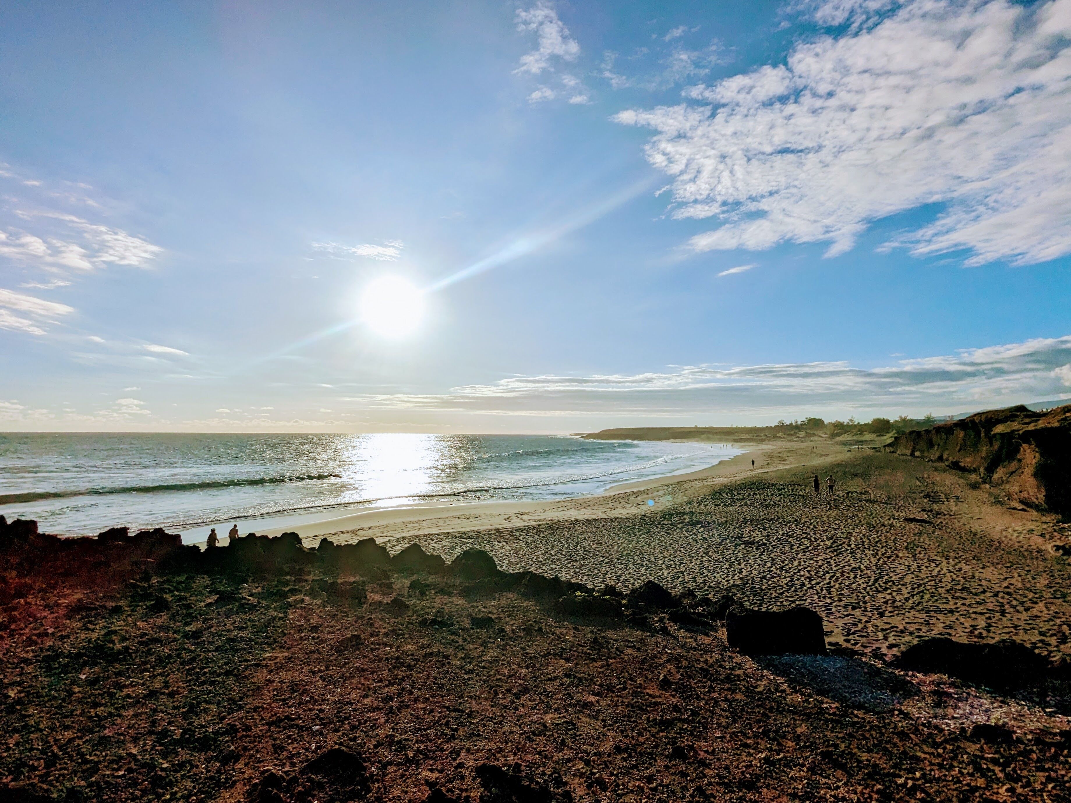 Une plage avec un rivage rocheux et une mer calme sous un ciel dégagé.