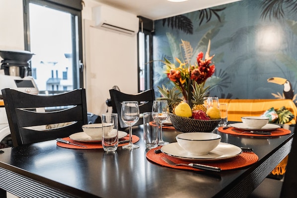 A dining table set with plates, bowls, glasses, and a fruit bowl.