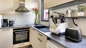 Una cocina moderna con extractor de acero inoxidable, horno empotrado, tostadora y cafetera.