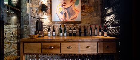 Zona de bar con mostrador de madera que exhibe varias botellas y vasos.
