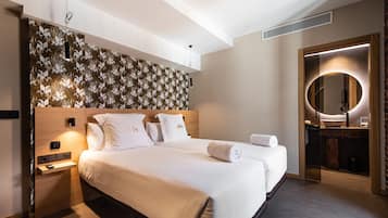A modern hotel room with a large bed, a bedside table, a mirror, and a wall with a floral pattern.