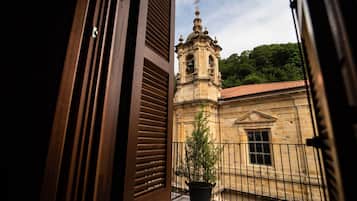 Vista de un edificio histórico con un campanario, una planta en maceta y una barandilla de balcón.